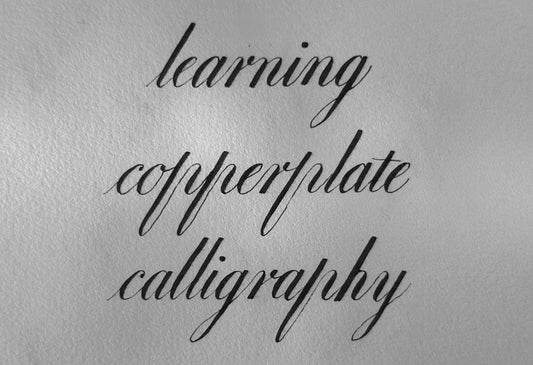 The words learning copperplate calligraphy written by hand, showing fine hairlines and shaded downstrokes.