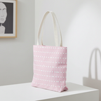 Pink geometric all-over tote bag with cream cotton handles, minimalist pattern.
